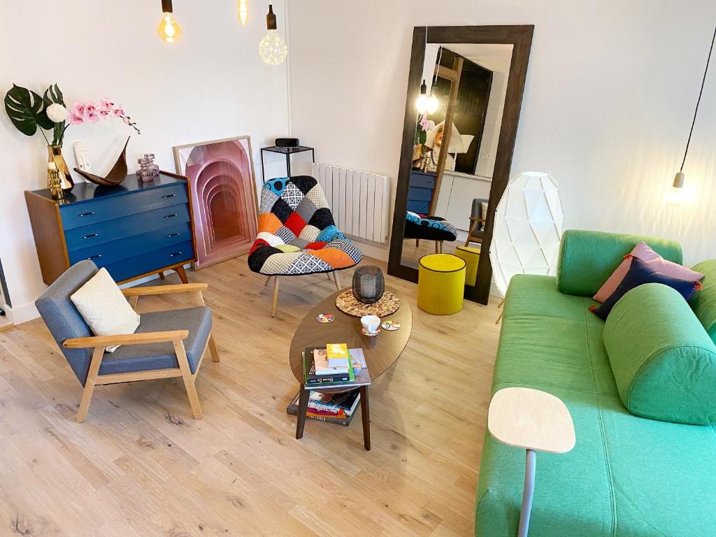 ein Wohnzimmer mit einem grünen Sofa und Stühlen in der Unterkunft Duplex lumineux, coloré, atypique face cathédrale in Saint-Brieuc