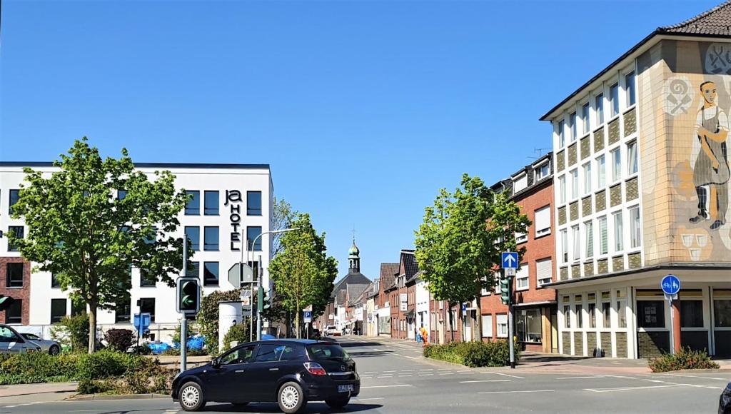 un coche negro conduciendo por una calle de la ciudad con edificios en JaHotel, en Geldern