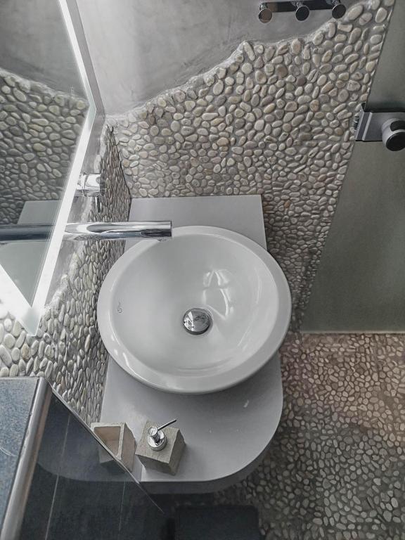 a white sink in a bathroom with a stone wall at Haraki Village in Haraki