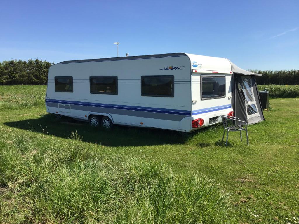 洛肯的住宿－Løkkensvejens bondegårds ferie，停在田野上的白色和蓝色大篷车