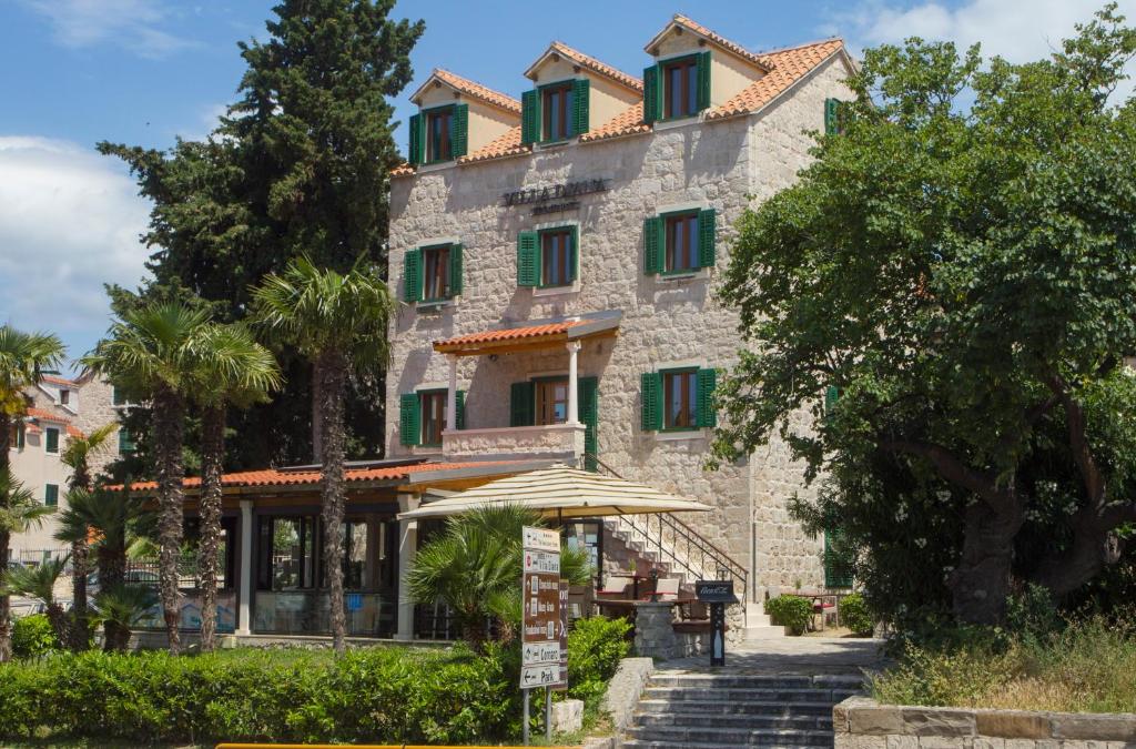 un gran edificio de piedra con ventanas con contraventanas verdes en Hotel Villa Diana, en Split