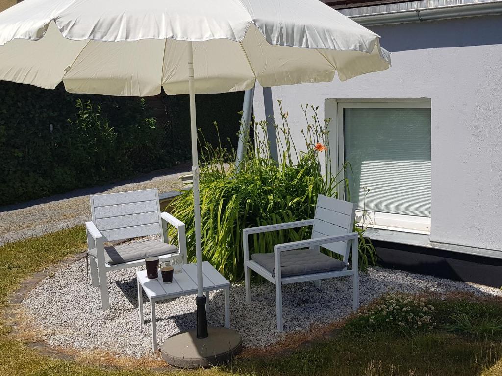 zwei Stühle und ein Regenschirm neben einem Tisch in der Unterkunft Apartment Mai in Elmenhorst