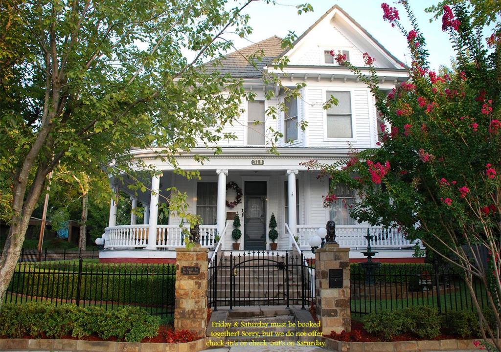 Uma casa branca com um portão à frente. em The Gables Inn em Hot Springs