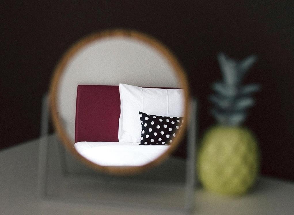 a mirror reflecting a room with a pillow and a pineapple at Hotel Central (kontaktloser Check-In) in Heilbronn