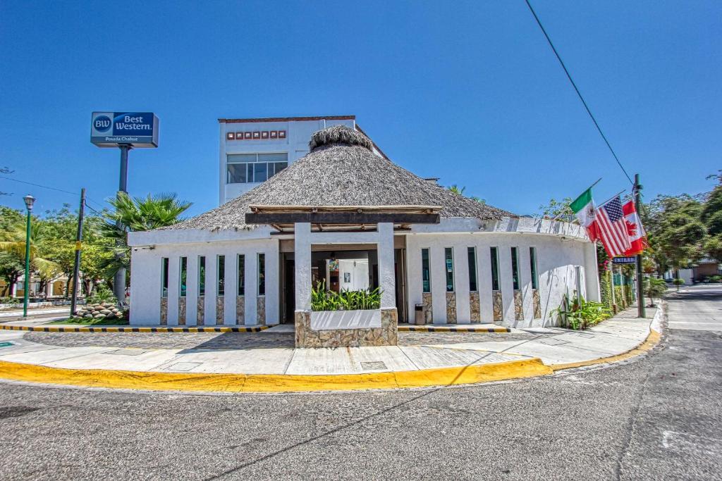 un bâtiment situé dans une rue avec des drapeaux devant elle dans l'établissement Best Western Posada Chahue, à Santa Cruz Huatulco