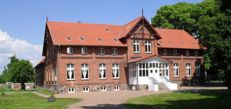 ein großes Backsteingebäude mit rotem Dach in der Unterkunft Gutshof Kämmerich in Altkalen