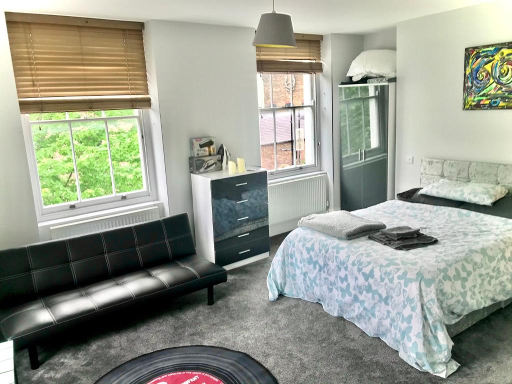 a bedroom with a bed and a couch and two windows at Camden Guest House Super king or Double Bedroom in London