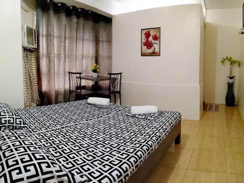 a bedroom with a black and white bed and a table at Thirdy's Place Hostel in Legazpi
