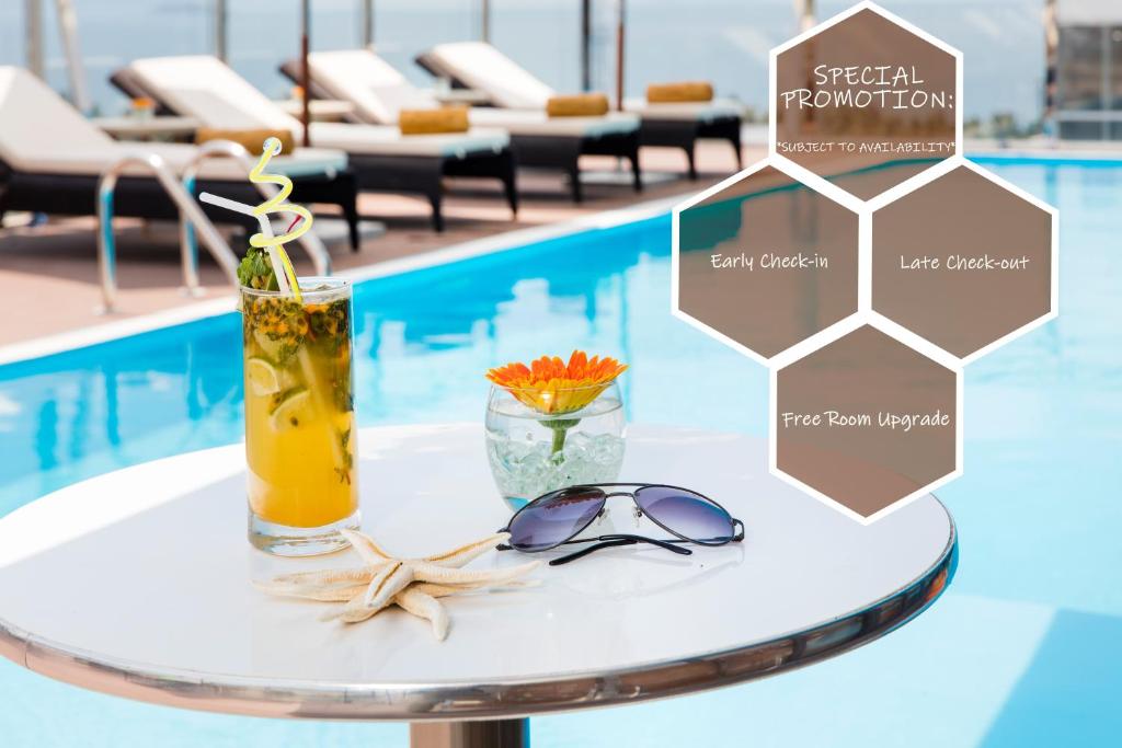 un tavolo con un drink e occhiali da sole in cima a una piscina di Stella Maris Nha Trang Hotel a Nha Trang