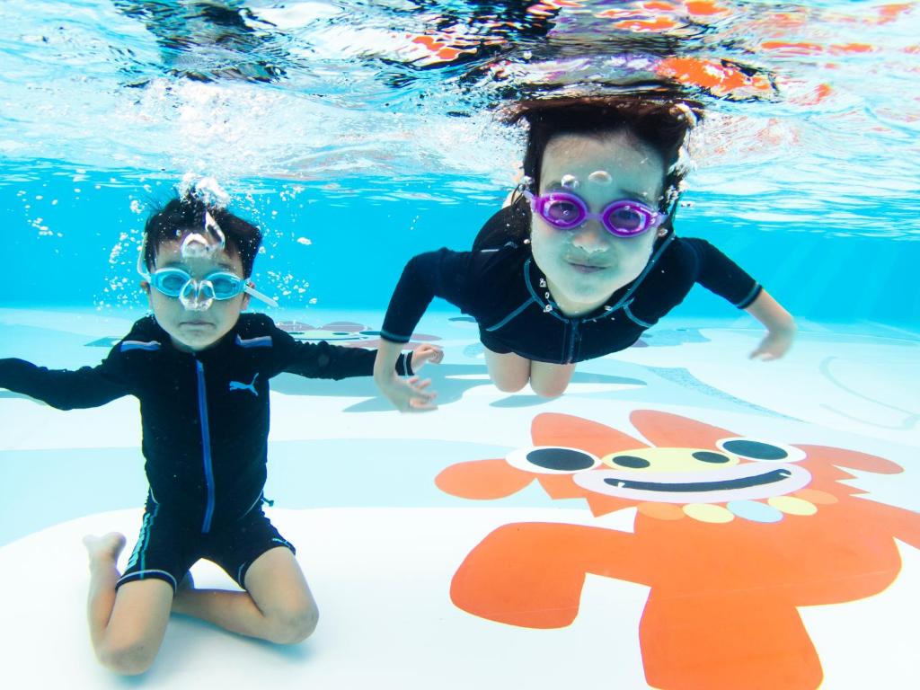 two young children are swimming in the water at Hotel Ocean (Kokusai-Dori) in Naha
