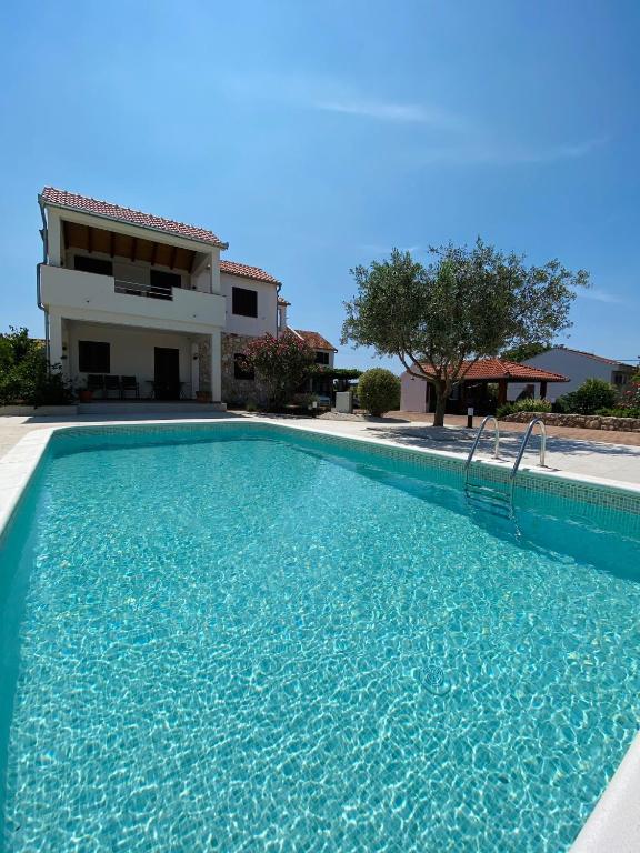 a swimming pool in front of a house at Apartmani Svemir in Drage