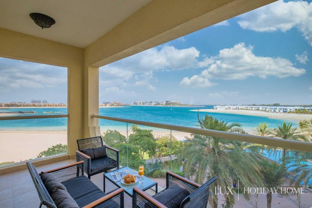 a balcony with chairs and a view of the beach at LUX - The Shoreline Beach House in Dubai
