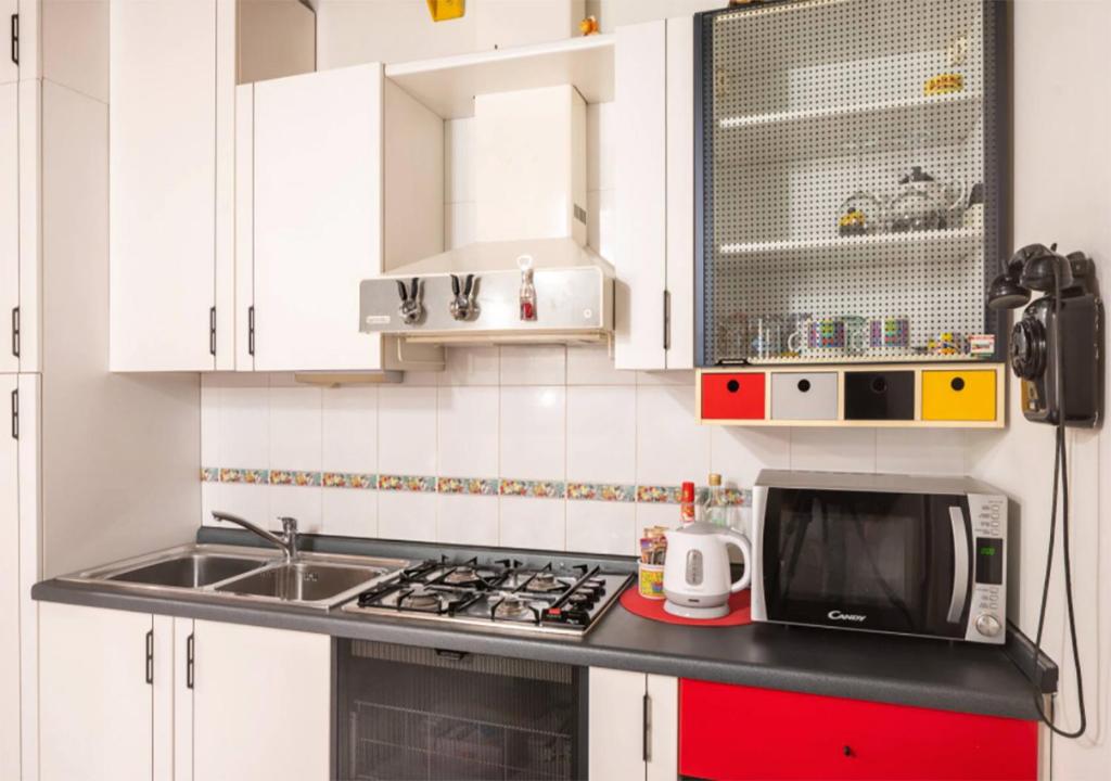 kuchnia z białymi szafkami, zlewem i kuchenką mikrofalową w obiekcie BnButler - Navigli Apartment - Vicolo Lavandai w Mediolanie