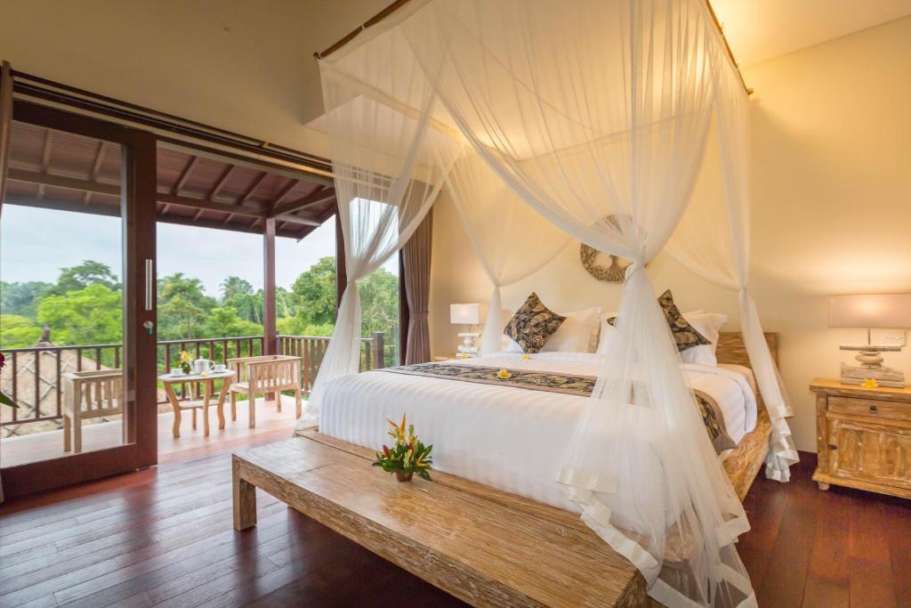 a bedroom with a canopy bed and a balcony at Villa Atap Padi by Nagisa Bali in Ubud