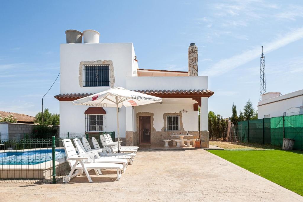 Casa blanca con sillas y piscina en Las Alas del Sol 2, en Vejer de la Frontera