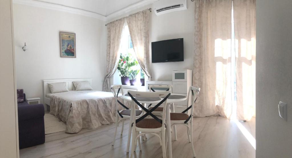 een kamer met een tafel en stoelen en een bed bij The GardenApartments in Odessa