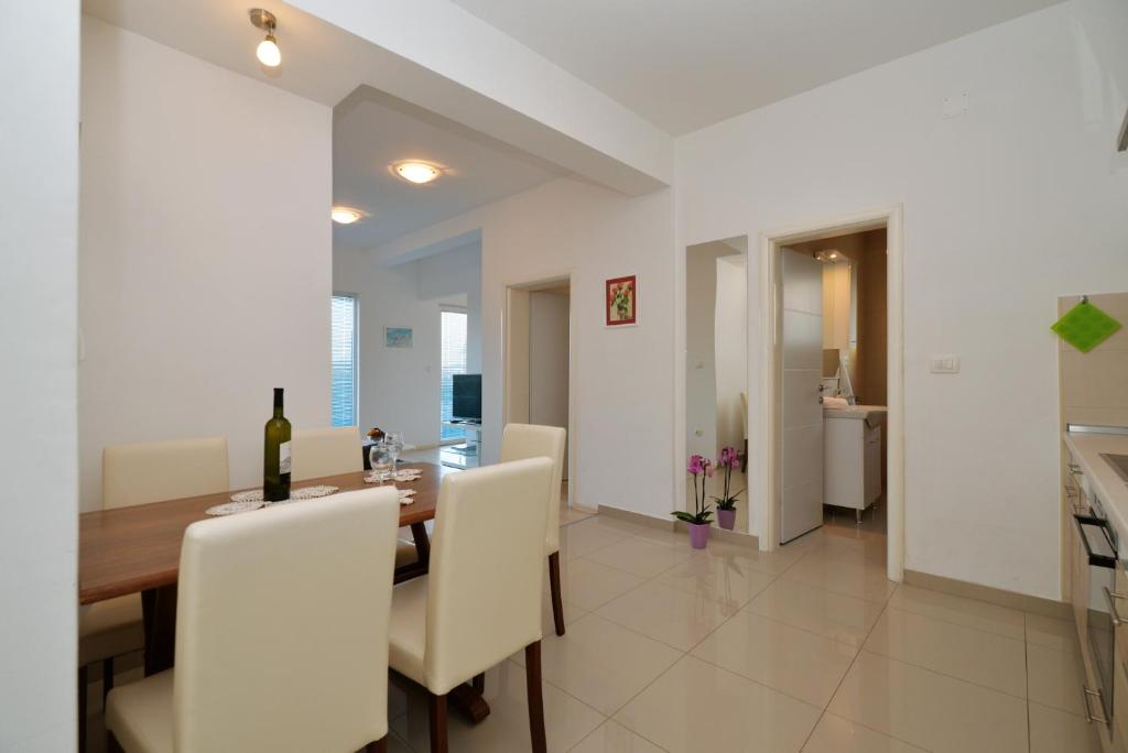 a dining room with a wooden table and white chairs at Apartman Lunga, Murter in Murter