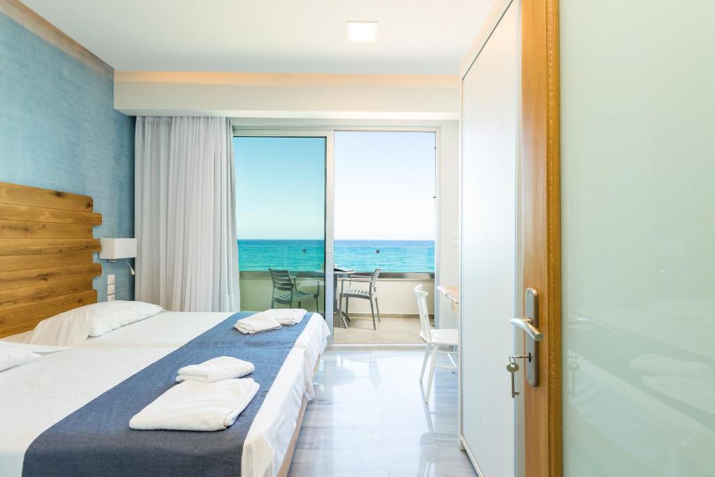 a bedroom with a bed and a view of the ocean at Meltemi Coast Suites in Rethymno