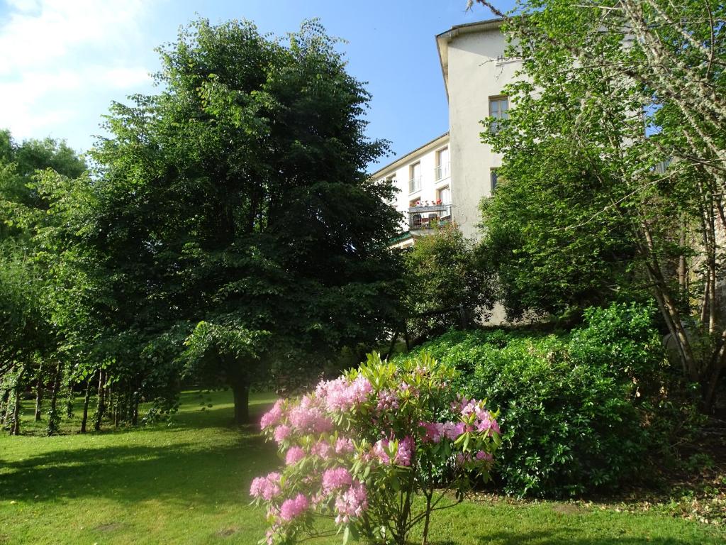 un jardín con flores rosas frente a un edificio en Hôtel Ambroise, en Uzerche