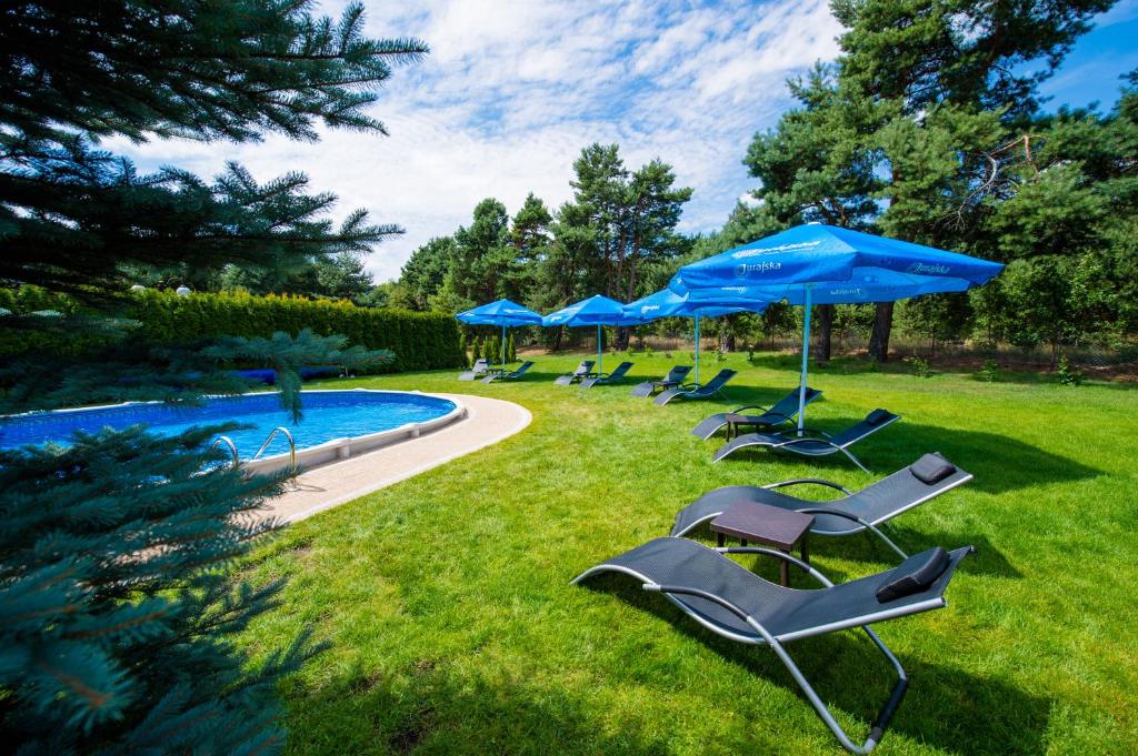 a group of chairs and umbrellas next to a pool at Hotel Ostaniec in Kroczyce