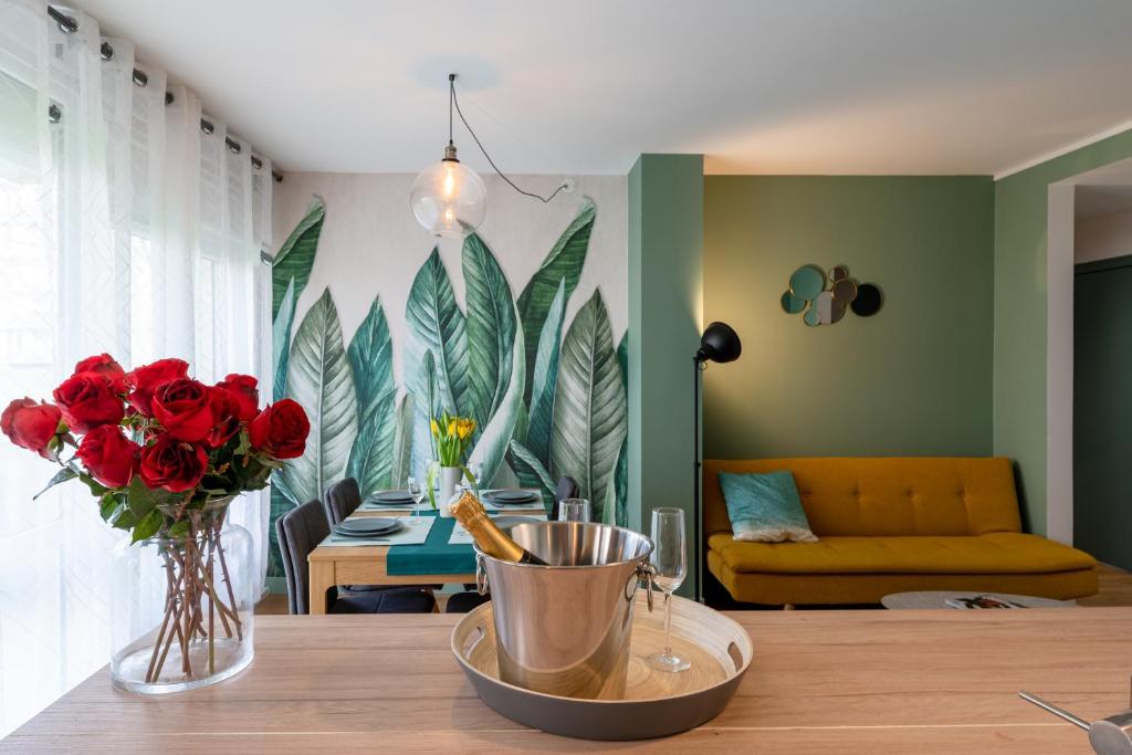 un salon avec une table et un vase de roses rouges dans l'établissement Le Romanesque, à Mont-Saint-Aignan