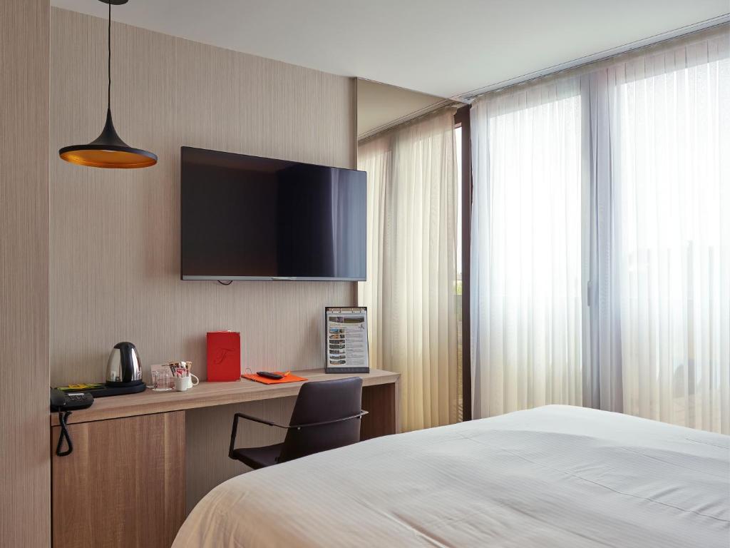 a hotel room with a bed and a desk and a tv at Le Florentin in Florenville