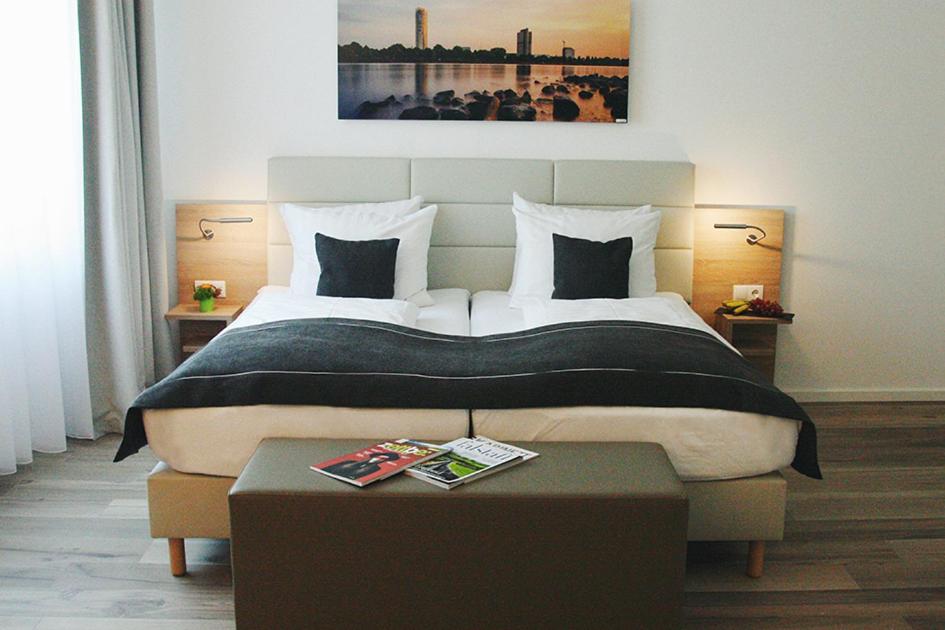 Un dormitorio con una cama grande y una mesa enfrente. en Four Stars by City Hotel, en Meckenheim