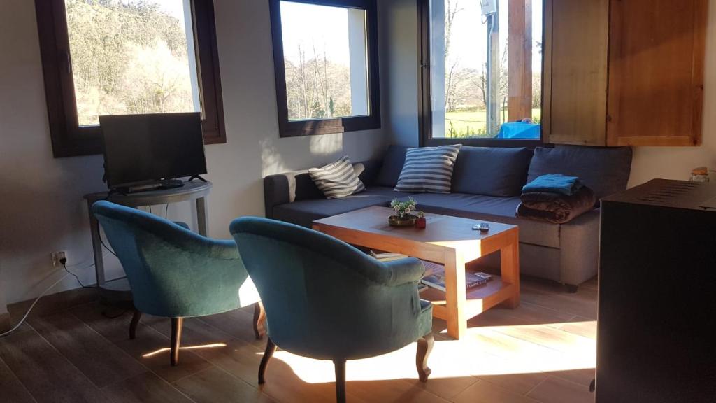 uma sala de estar com um sofá, cadeiras e uma mesa em Casita Junto al Río Deva em Vilde