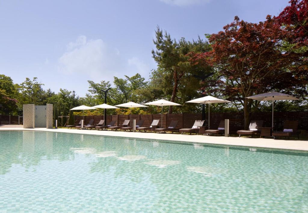 a swimming pool with chairs and umbrellas at Lahan Select Gyeongju in Gyeongju