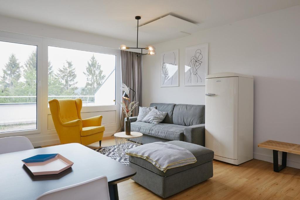 a living room with a couch and a refrigerator at Welcome in - Ferienwohnung 'Tremonia', gegenüber der Piste mit Balkon in Winterberg