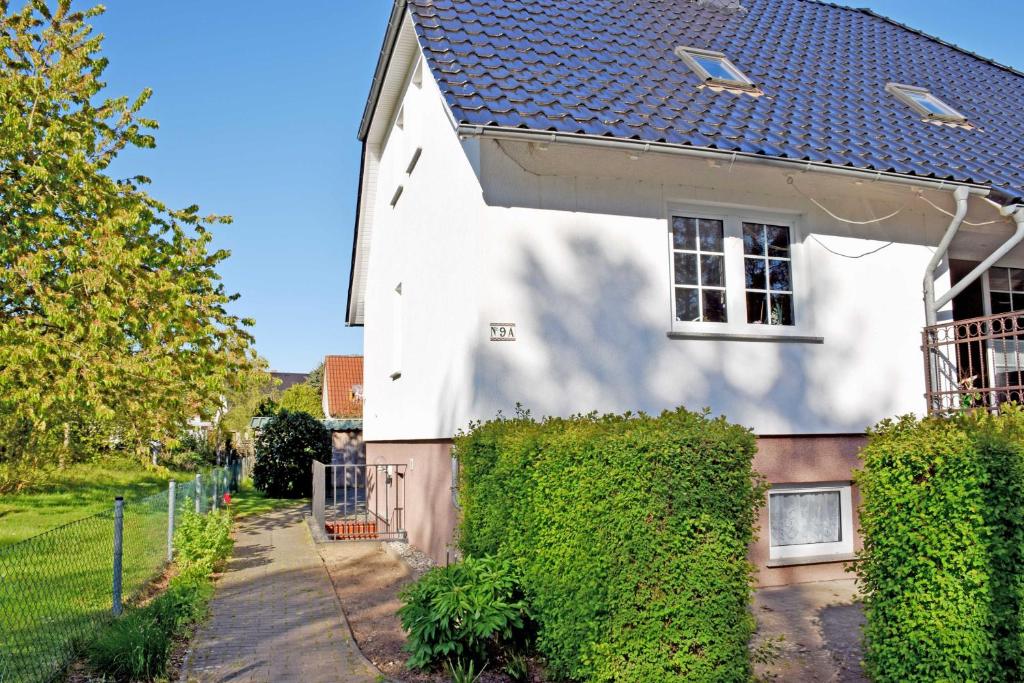 a white house with a hedge in front of it at Ferienwohnung Marie an der Granitz in Schmacht