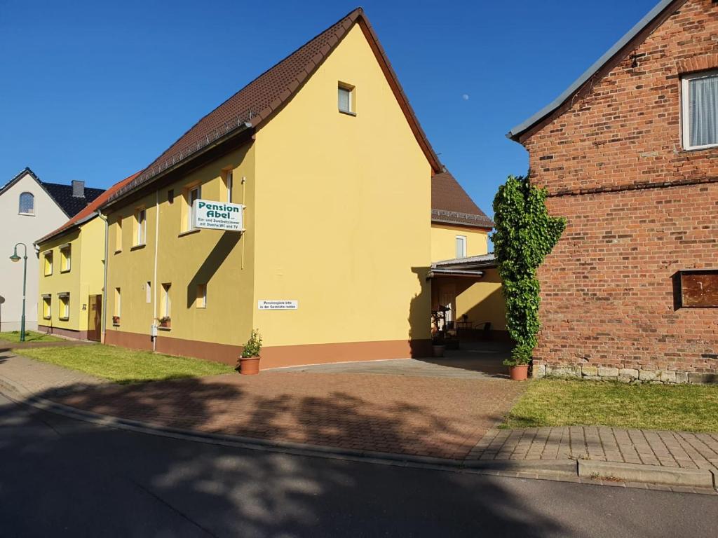 ein gelbes Gebäude neben einem Backsteingebäude in der Unterkunft Gasthof Zum Amboss in Lützen