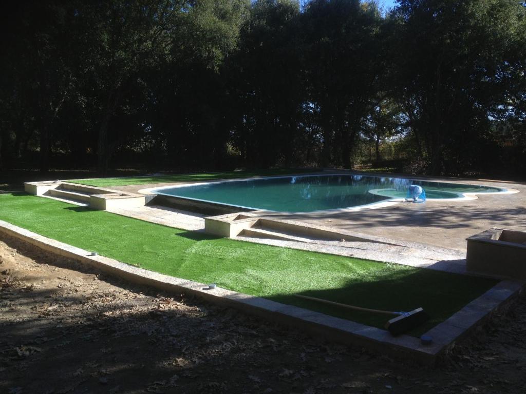 una piscina en un patio con césped verde en Apartamentos Rurales La Oropendola, en Jaraíz de la Vera