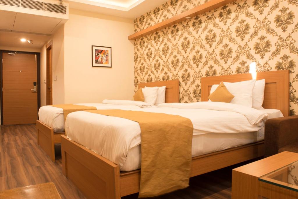 a hotel room with two beds in a room at Stayotel Kolkata Airport in Kolkata