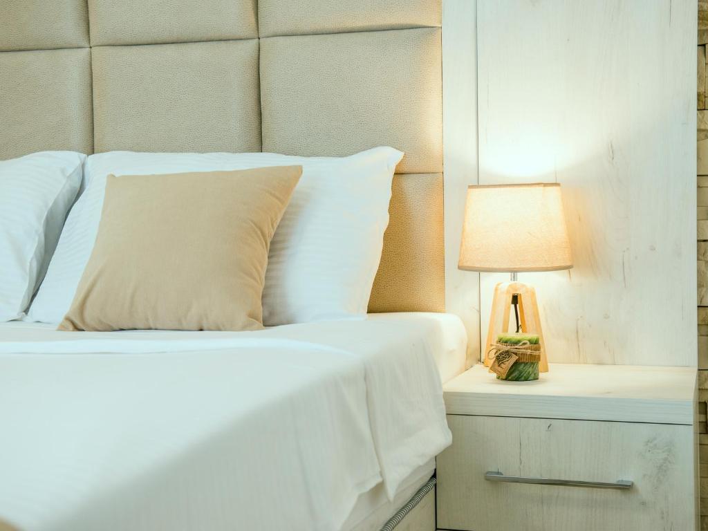 a bed with white sheets and a lamp on a night stand at Square Point Apartments in Kotor