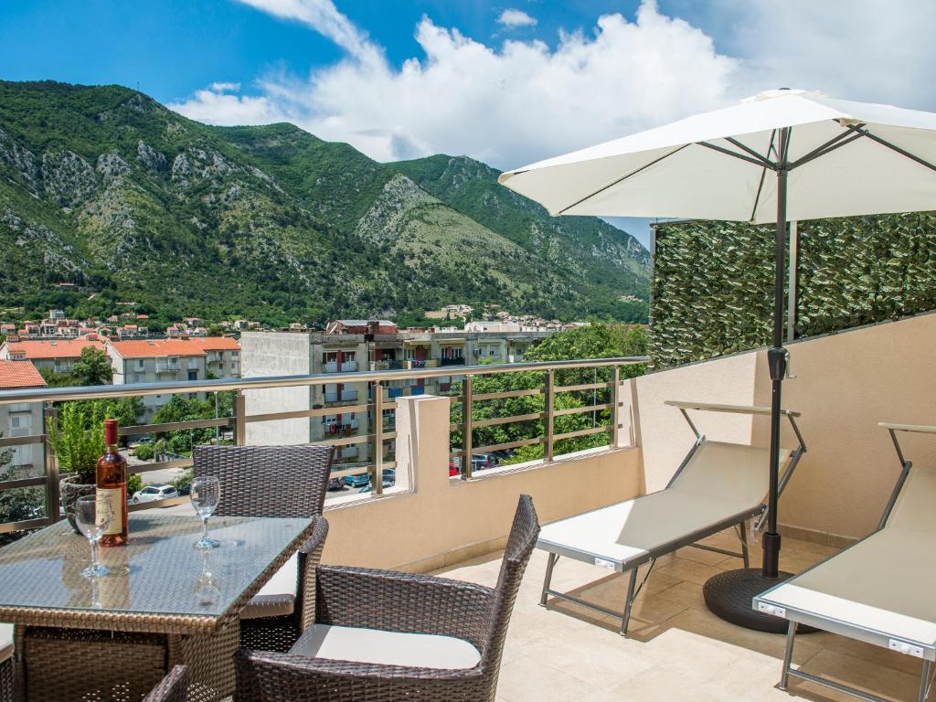 a balcony with a table and chairs and an umbrella at Square Point Apartments in Kotor