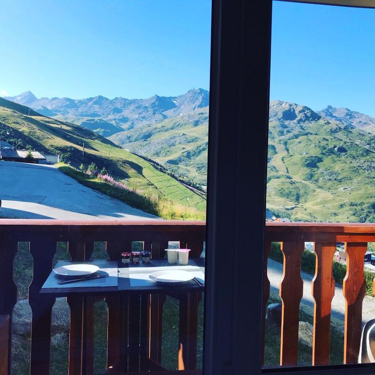 une table sur un balcon avec vue sur les montagnes dans l'établissement Le Necou - Reberty 2000, aux Menuires
