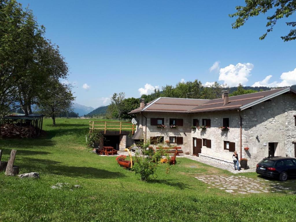 a large stone house with a yard in front of it at Chalet Maso Pino in Castello Tesino