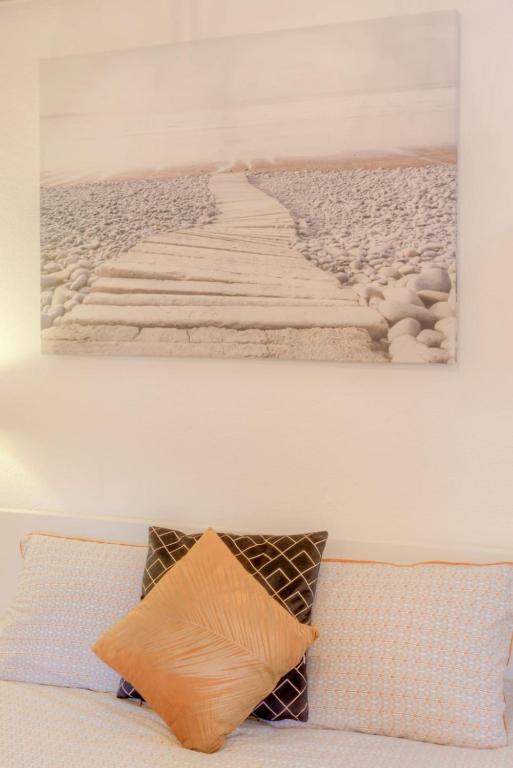 a pillow sitting on a couch with a painting on the wall at #5 Flower Markets Place 1Min to beach &amp; Saleya in Nice