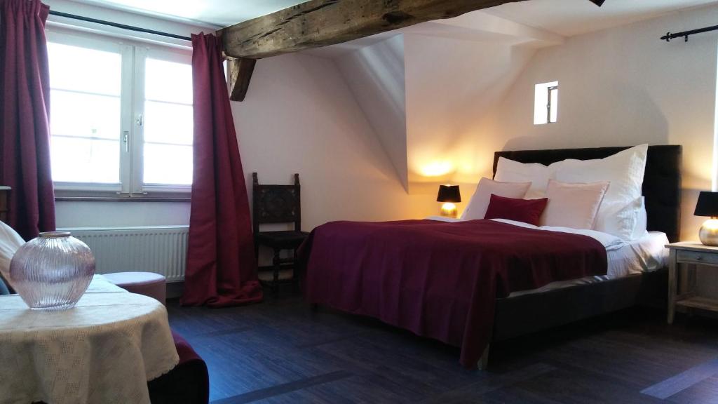 ein Schlafzimmer mit einem Bett mit einer roten Tagesdecke in der Unterkunft Manoir -1654- historisch schlafen in Monschaus Altstadt in Monschau