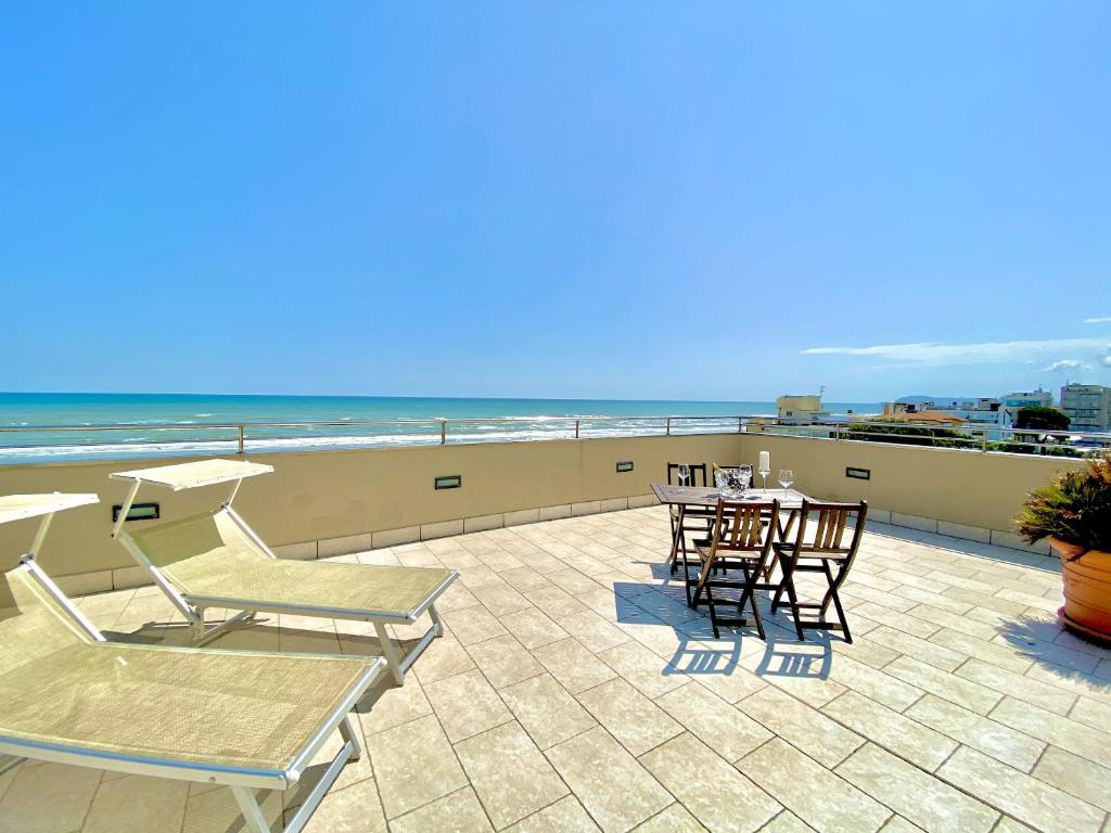 een patio met tafels en stoelen en het strand bij Hotel Avana in Riccione