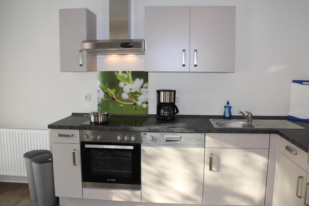 a kitchen with white cabinets and a stove top oven at Königin Victoria - Appartement mit Saunanutzung in Burgbernheim