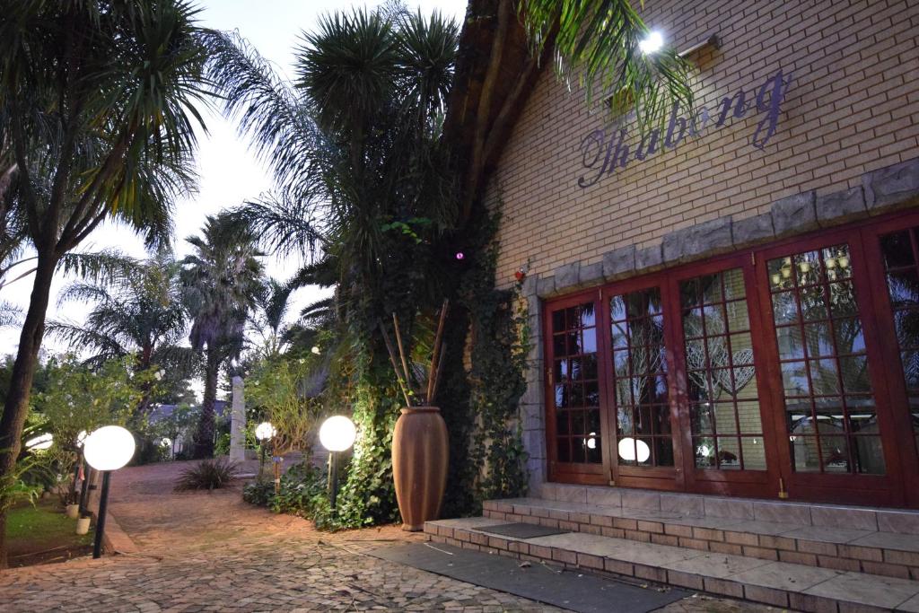 a building with a palm tree in front of it at Thabong Bed and Breakfast in Brakpan