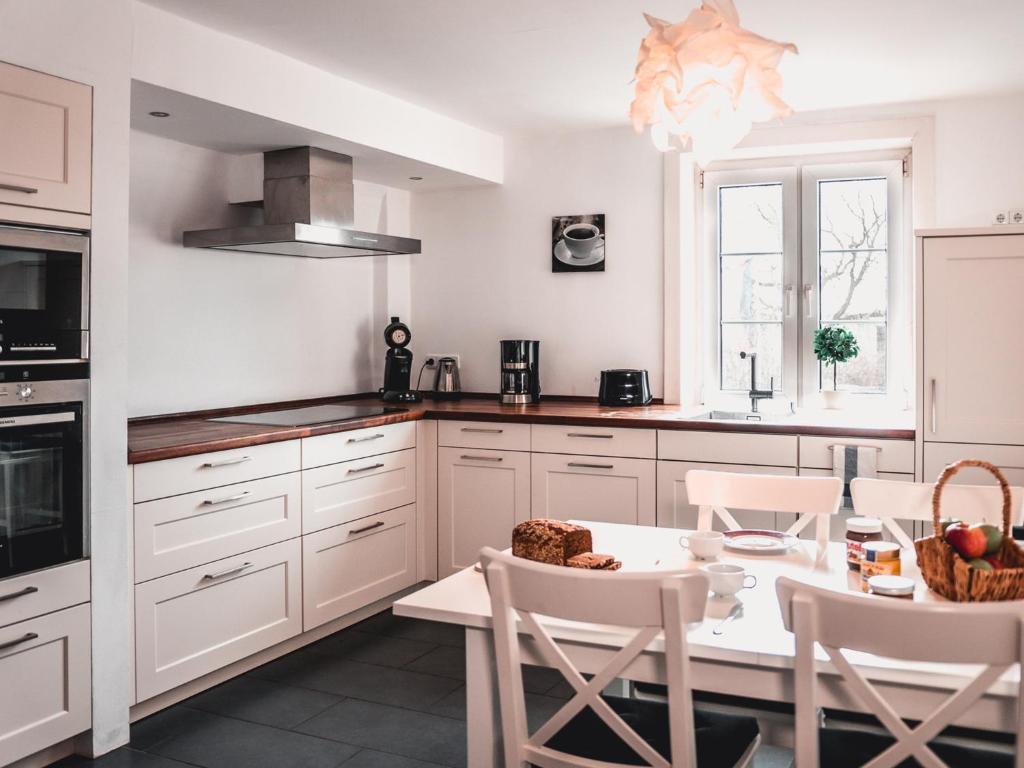 une cuisine avec des placards blancs et une table avec des chaises dans l'établissement Bett4-you Pinneberg, à Pinneberg