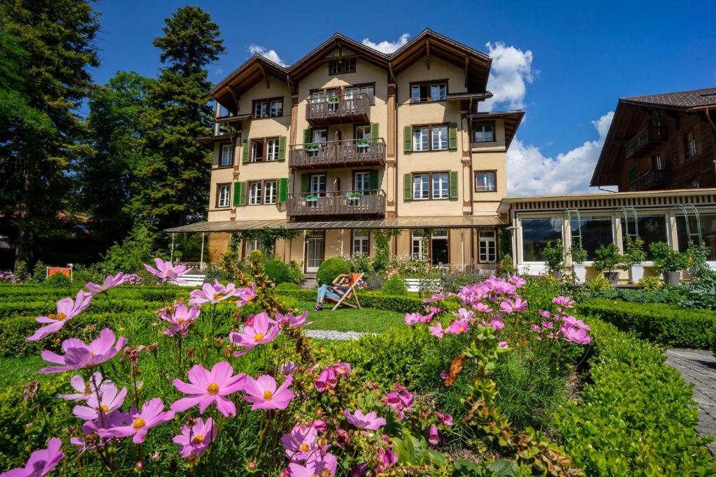 a large house with a large garden in front of it at Alpenrose Hotel and Gardens in Wilderswil