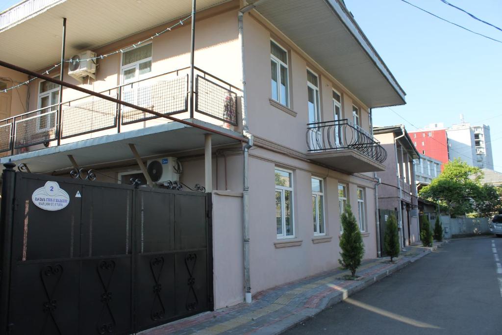a white house with a black gate on a street at Iren Apartment in Batumi