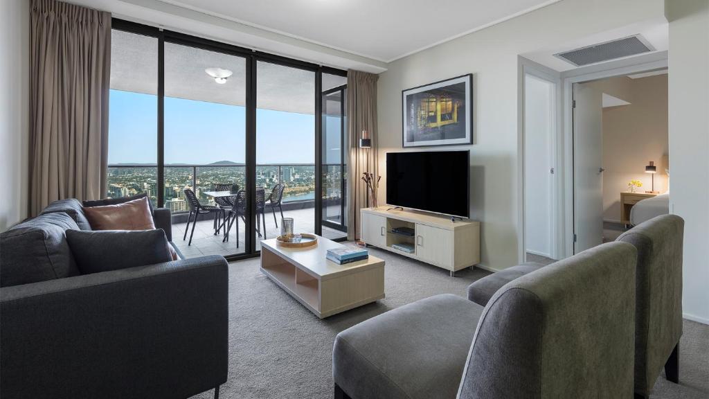 a living room filled with furniture and a tv at Oaks Brisbane Aurora Suites in Brisbane