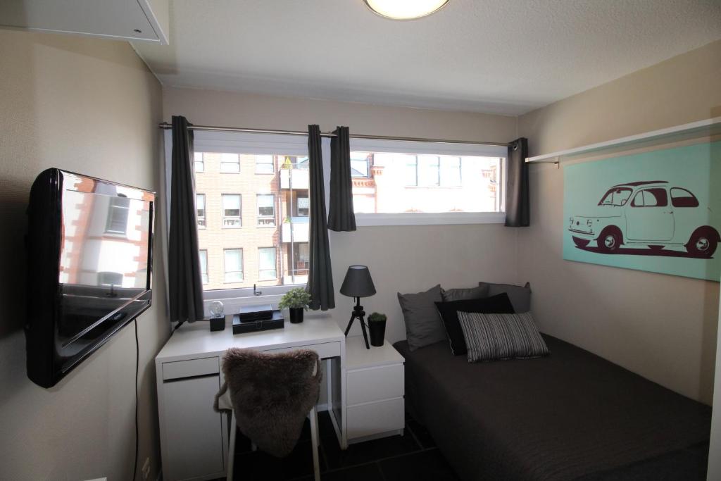 ein Wohnzimmer mit einem Sofa, einem TV und einem Fenster in der Unterkunft Kongensgate Apartments in Kristiansand
