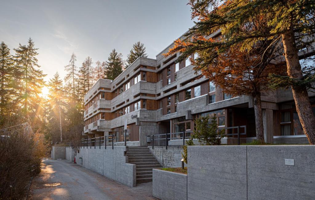 un edificio de apartamentos con una valla y árboles en Sport Resort Fiesch, Garni Goneri, en Fiesch