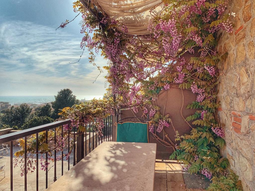 een balkon met paarse bloemen en een groene stoel bij Castel del Mare in San Vincenzo
